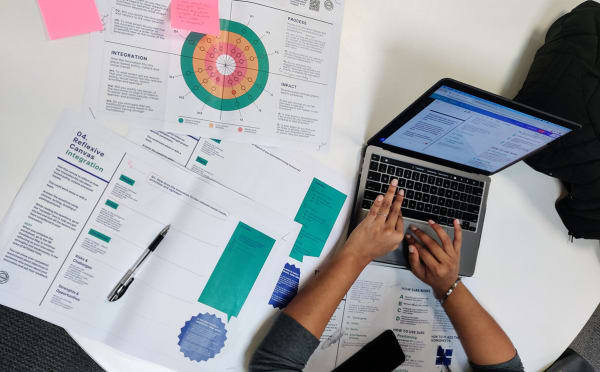 Image of a laptop sitting on a table of notes.