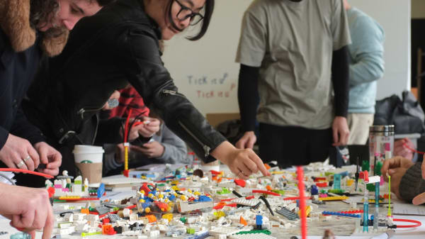 Students working at a table with legos in a creative workshop.
