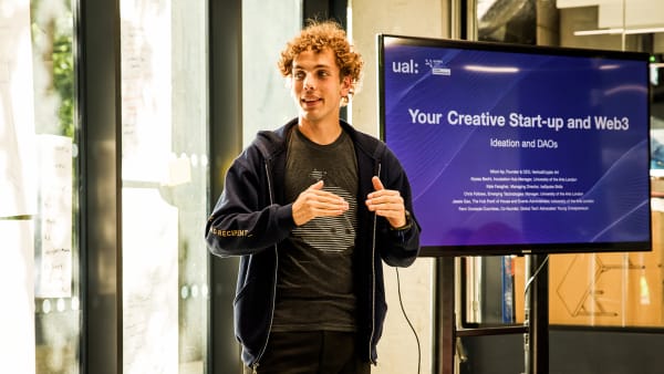 Boy presenting in a room in front of a large television screen.