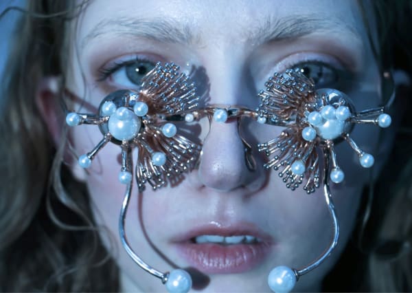 Female model wearing pearl and gold embellished glasses.