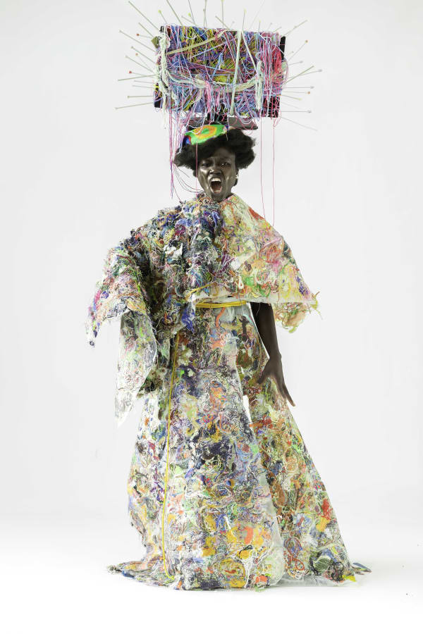 Figure wearing large garments made from smaller colourful pieces