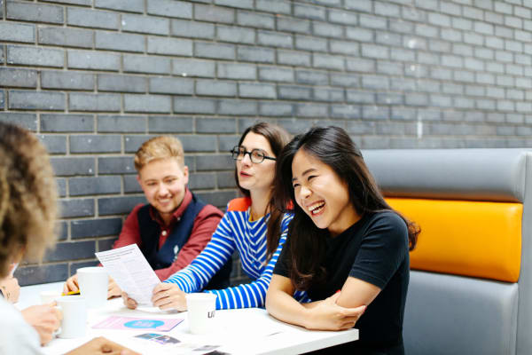 Four students sitting at a table smiling and laughing