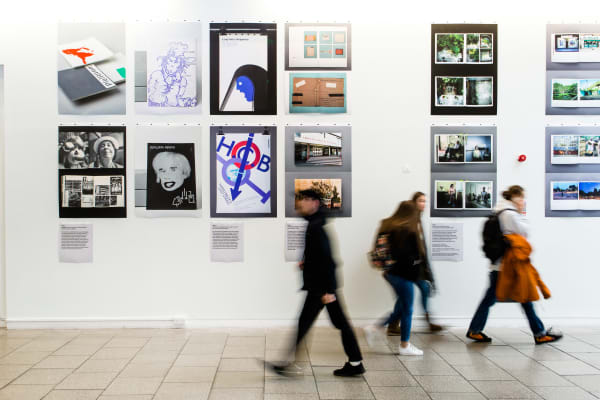 People walking past an exhibition wall, with their movement blurred.