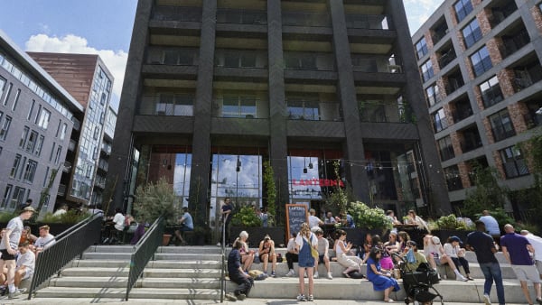 Building with people gathered on steps in front of it in the sun.