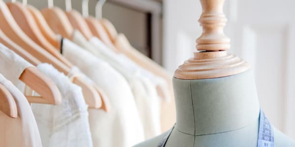 A mannequin in front of a rail of clothes.