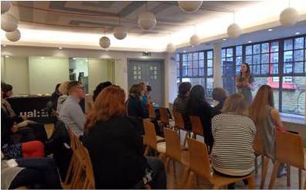 People seated listening to woman speaking 