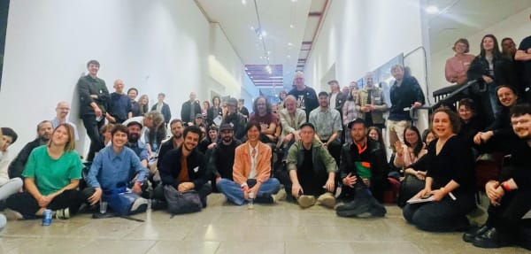 In the Field 2 symposium participants posing for a picture in an exhibition hall.