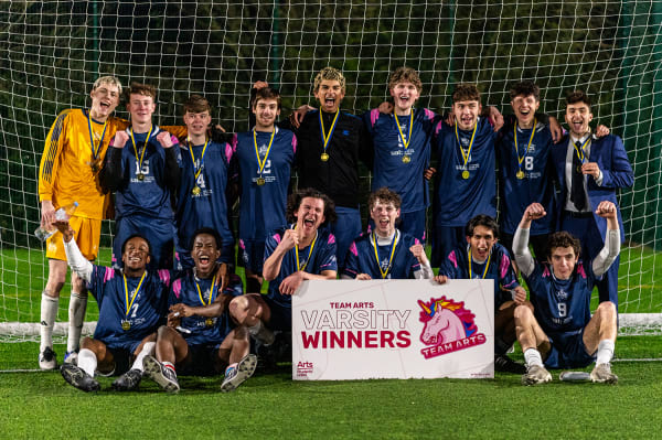 A football team at the end of the match celebrating with their trophy.