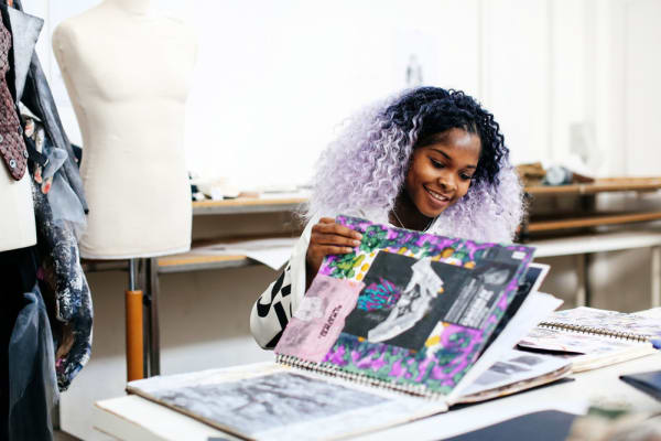Female student with purple hair flicking through her sketchbook