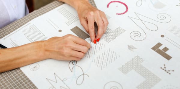 Woman embroidering text onto paper