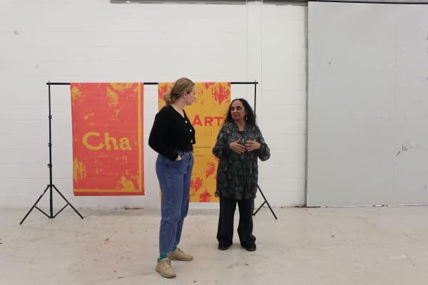 two people chatting in front of posters with text stating ChArt