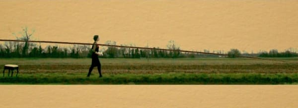 Still image of a woman walking across the field. The image has a horizontal line drawn across as though it.