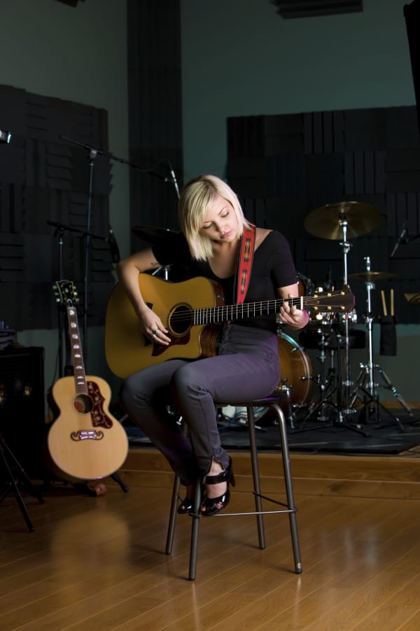 Woman sitting on a stool playing guitar