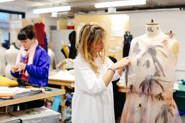 Girl working in studio, adjusting a garment on a mannequin 