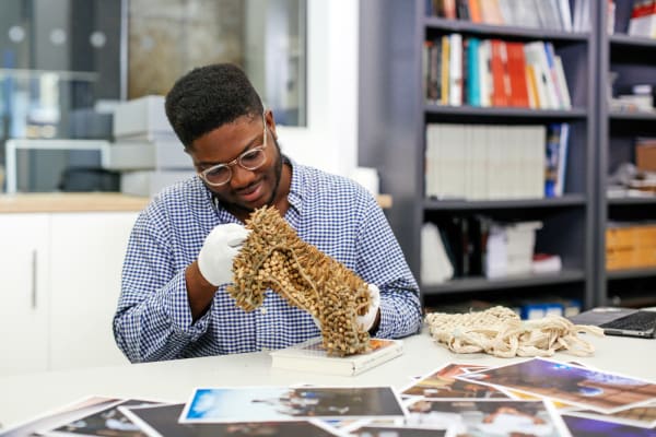 Man in white gloves holding gold object from the archives, BA Culture, Criticism and Curation, Archive Research by Damilola Ayo-Vaughan, Copyright holder: Alys Tomlinson