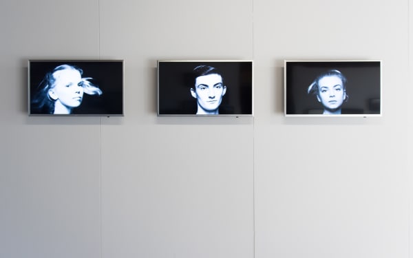 Three televisions mounted on a wall with videos of dancers spinning