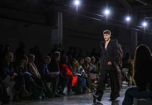 Model on catwalk in black suit