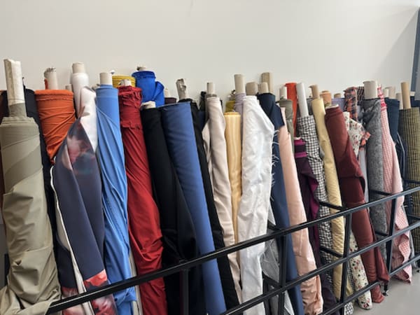 Fabric rolls leaning against a wall in the Garment Store at East Bank. Photography by Jo Sait.