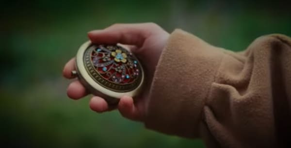 Close up of a hand holding an object on a green background