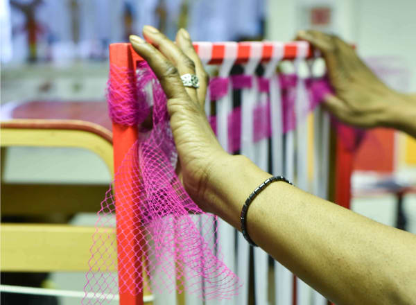 Someone's hands holding netted material against a frame – making a chair