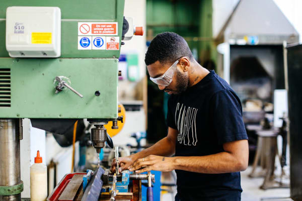 Boy in goggles operating a wood cutting machine 