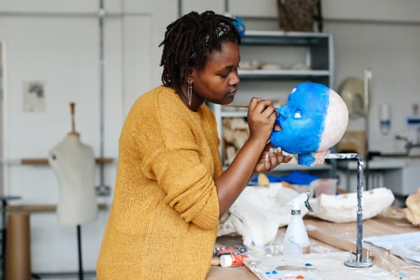Girl painting a model of a head in studio 