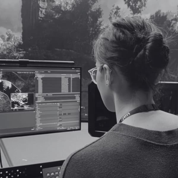 Myriam Cherif, looking at a number of computer screens, with the UAL XR Lab in the background 