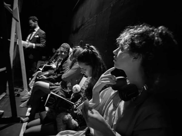 A row of people sat down reading from booklets