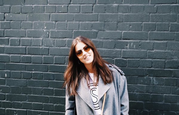 Natalie Grogan in front of a wall, wearing sunglasses