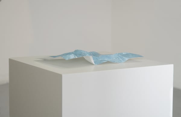 Crumpled photograph on a white plinth