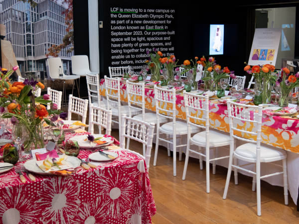 Dinner table set up with white chairs and colourful flowers