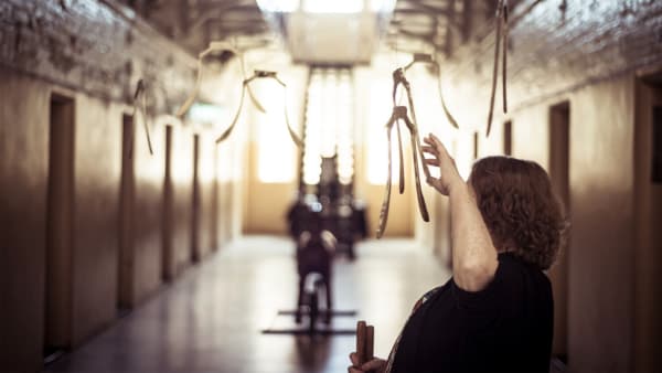 Man touching hanging sculpture in a room.
