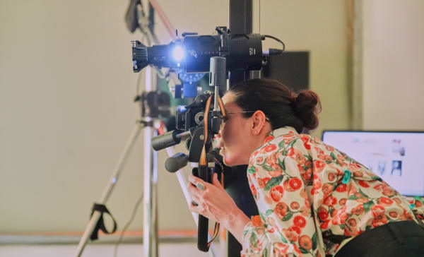 Student using a camera and other technical equipment within a studio space.