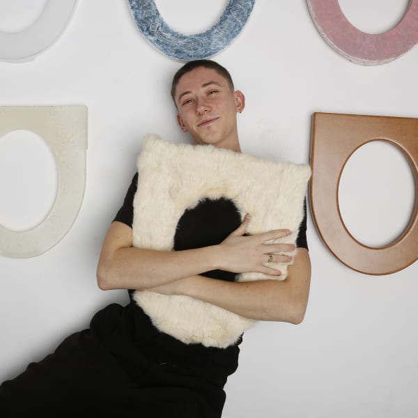 Photograph of a man holding a furry object similar to the shape of a toilet seat