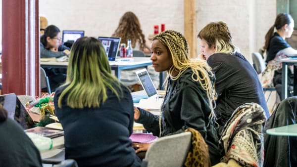 Students working at tables inside Central Saint Martins' Library