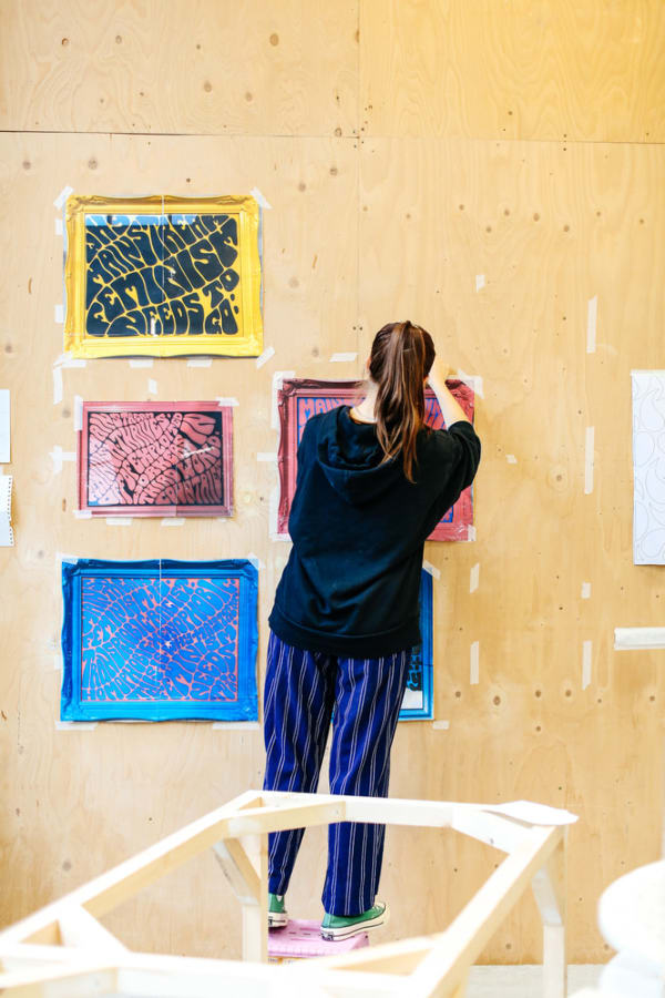 Girl hanging prints on a wall 