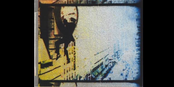 A yellow and blue negative of a man hanging from a clock