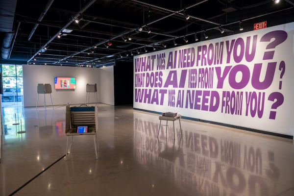 A photo of a gallery space. An exhibition on the wall reads 