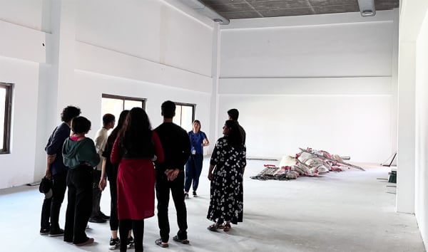 A group of people stand beside an exhibit in a large, white room.