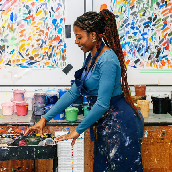 A student returns pots of ink from a trolley to a table in a printing studio