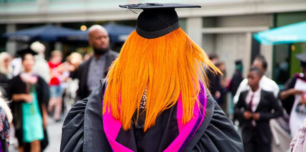 Student in full graduation robes walking towards the Royal Festival Hall