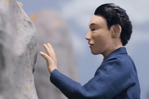 Still from animated film of character staring at a large rock.