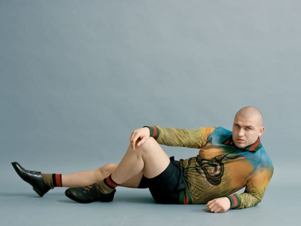 Older man posing on the floor in tight top and shorts.