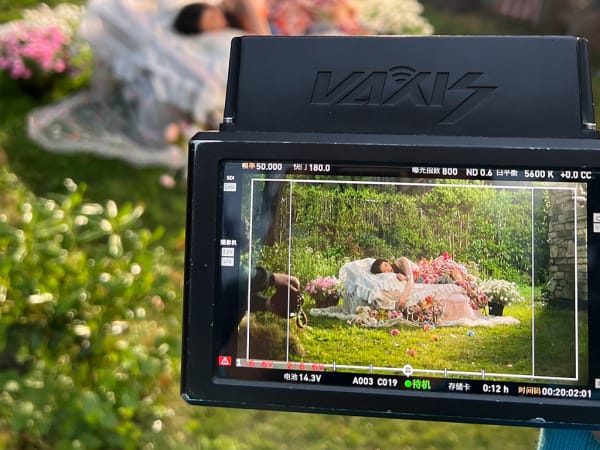 View from the lens of a camera of woman sleeping on bed of flowers.