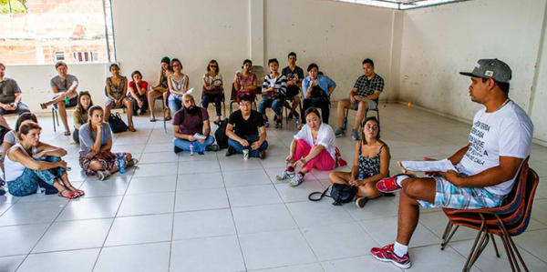 A man sat on a chair talking to people sat on the floor 