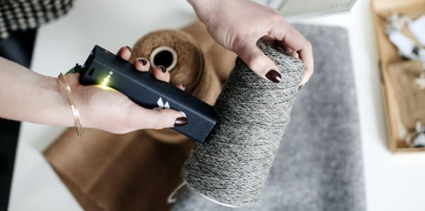 A persons hands using a digital tool to scan a piece of fabric 