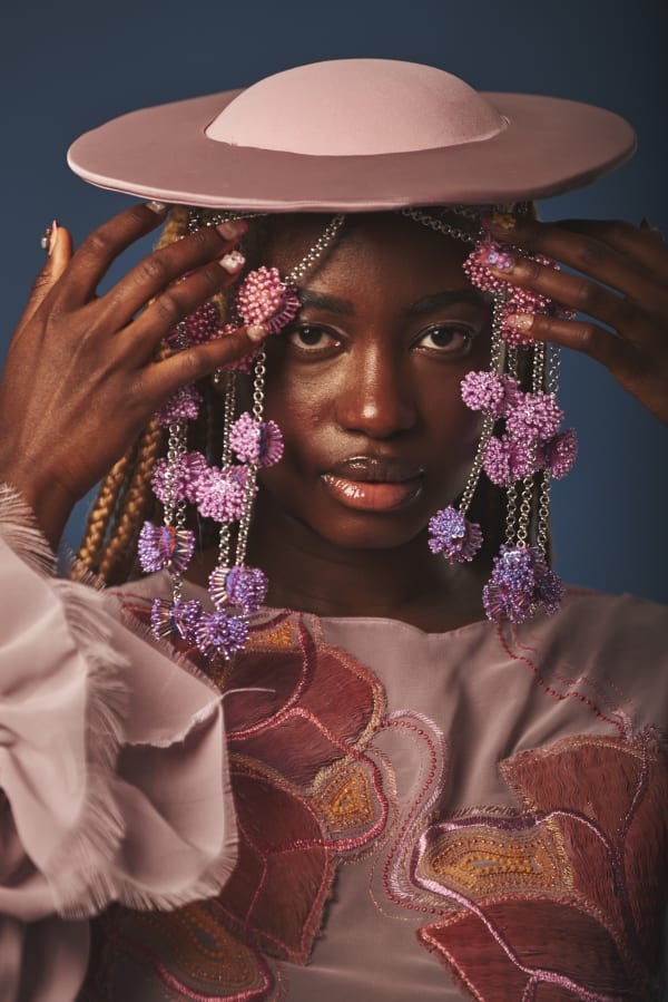 Black woman wearing a hat with garlands