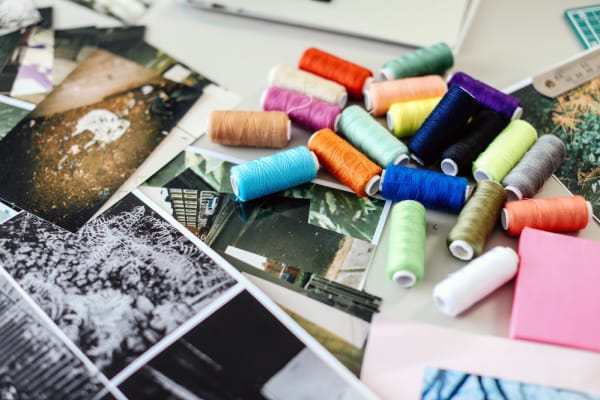 Pictures and different coloured thread on a table, International Preparation for Fashion, Tools of Danielle Tartaro, Copyright holder: Alys Tomlinson