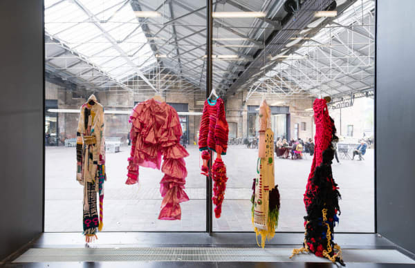 5 different pink and patterned costume designs hanging in a window display at Central Saint Martins.