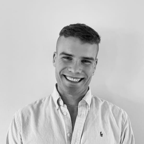 Freddie O'Reilly, Senior R&D Fellow in XR Textiles and Dress, wearing a white shirt, and smiling at the camera, in a black and white photo with a plain white background